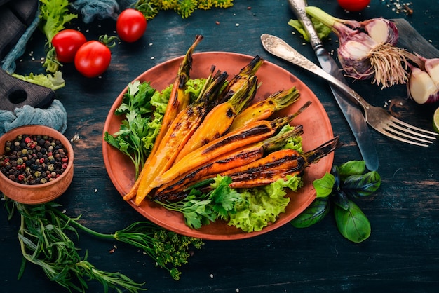 Grilled carrot in a plate with vegetables On a wooden background Top view Copy space