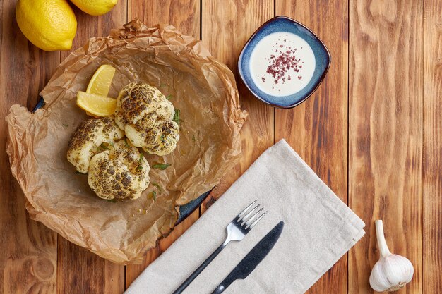 Grilled cauliflower with tahini, wooden background