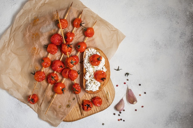 Grilled cherry tomatoes on skewers on baking paper