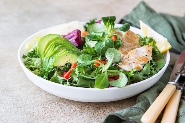 Grilled chicken breast, avocado, apple and bell pepper salad with salad leaves mix.