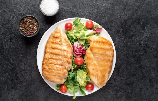 grilled chicken breast and cherry tomato salad on stone background