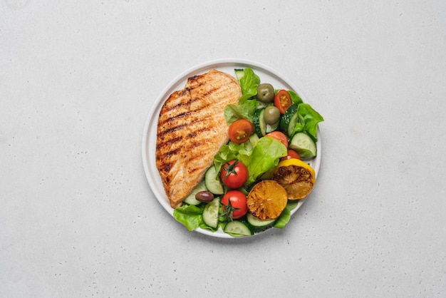 Grilled chicken breast fillet or poultry steak with fresh vegetable salad in white plate