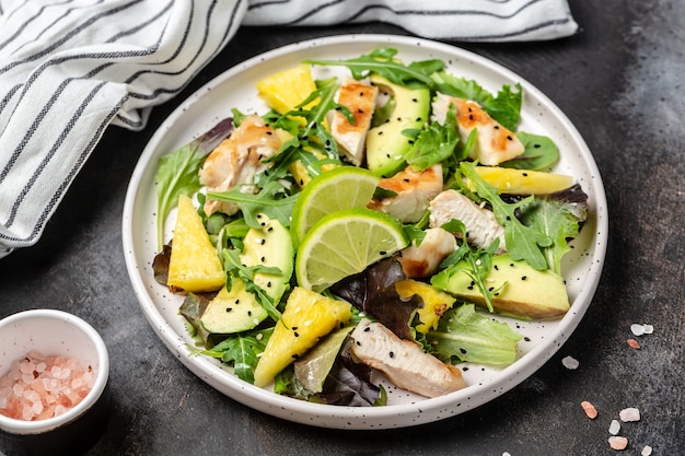 Photo grilled chicken breast salad with pineapple, avocado, green rocket salad lime