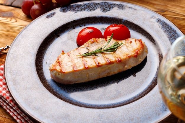 Grilled chicken breast served with cherry tomatoes on table close up