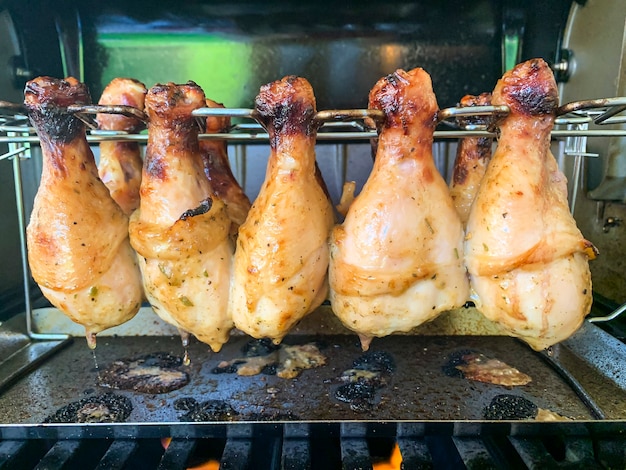 Grilled chicken drumsticks are cooked in gas grill.