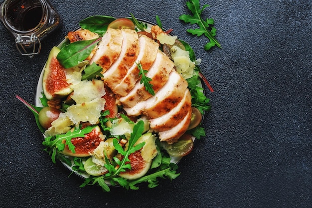 Grilled chicken fillet with fig grape arugula and chard salad Black table background top view