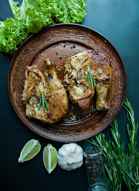 Photo grilled chicken in a grill pan vegetables on a dark background. 