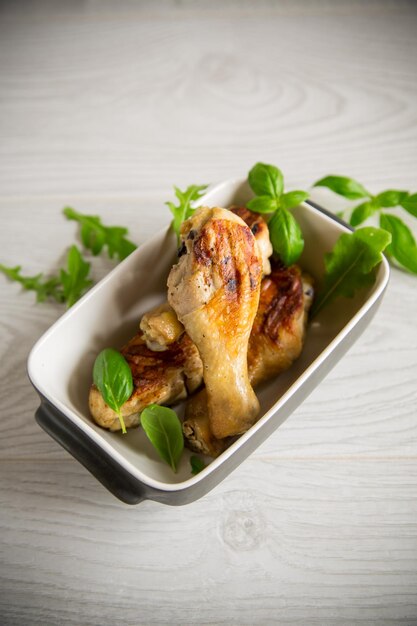 Grilled chicken legs fried with spices and herbs in a ceramic bowl