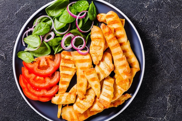 Grilled chicken strips on a plate with vegetables