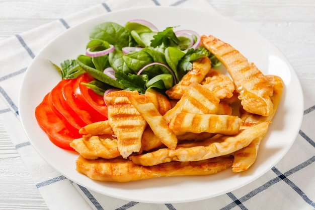 Grilled chicken strips on a plate with vegetables