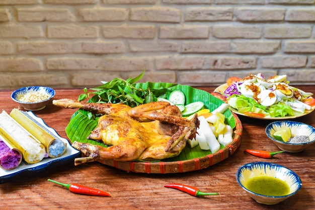 Grilled chicken in vietnamese style with colorful rice in bamboo, and boiled eggs on wooden table