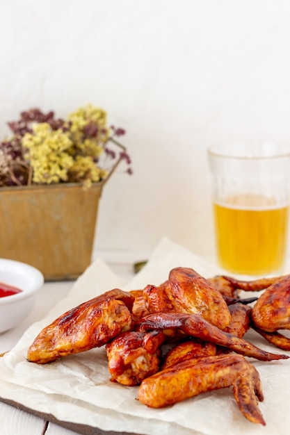 Grilled chicken wings with beer and red sauce on a wooden background. Snack to beer. Barbecue. Recipes.