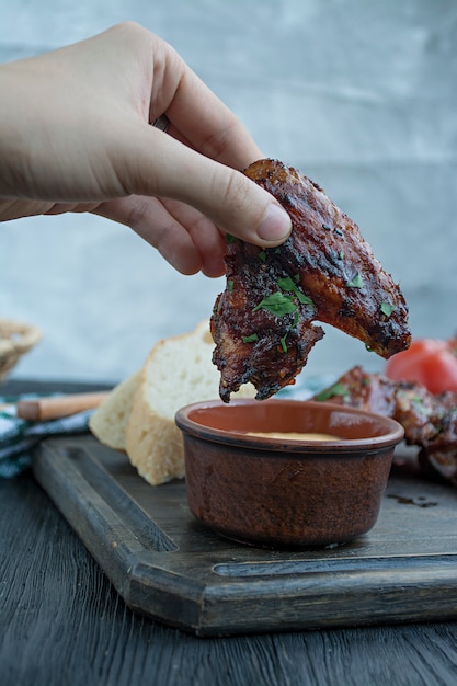 Photo grilled chicken wings with sauce and herbs.baked chicken wings in pan. dark wooden background.