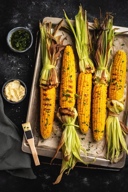 Grilled corn on a baking sheet, top view, dark, rustic style