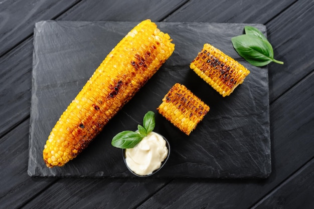 Grilled corn on a dark wooden background slices of sliced corn grilled on charcoal