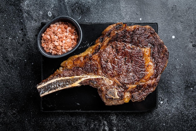 Photo grilled cowboy or rib eye with bone beef steak black background top view