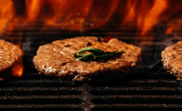 Grilled cutlet burger with flames raw beef steak on a BBQ grill banner menu recipe place for text top view