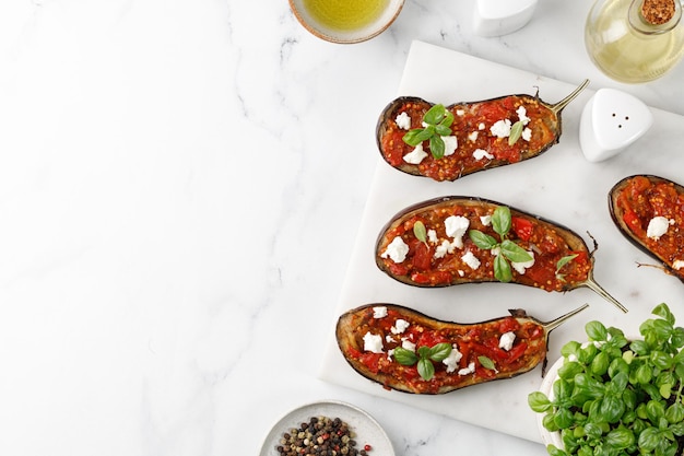 Grilled eggplant stuffed with chopped tomatoes on cutting board white background Top view copy space