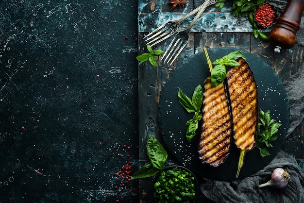 Grilled eggplant with basil on a black stone plate Top view Free space for your text