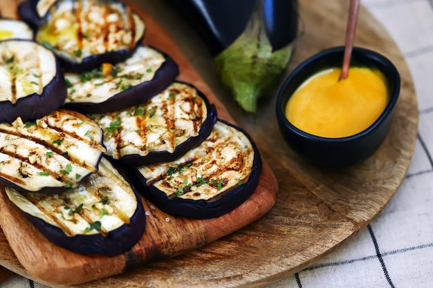 Grilled eggplant on a wooden board with honey mustard sauce