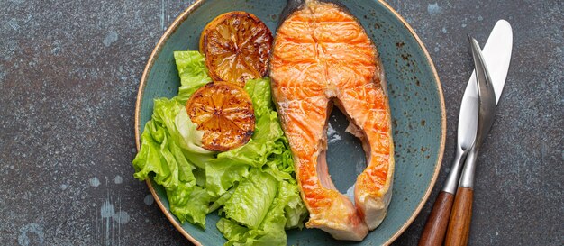 Photo grilled fish salmon steak and green salad with lemon on