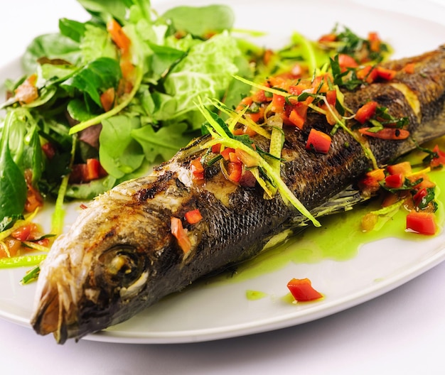 Grilled fish with vegetables on white plate