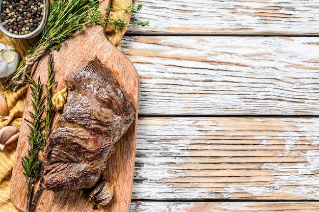 Grilled flank steak on a chopping Board with seasonings and spices