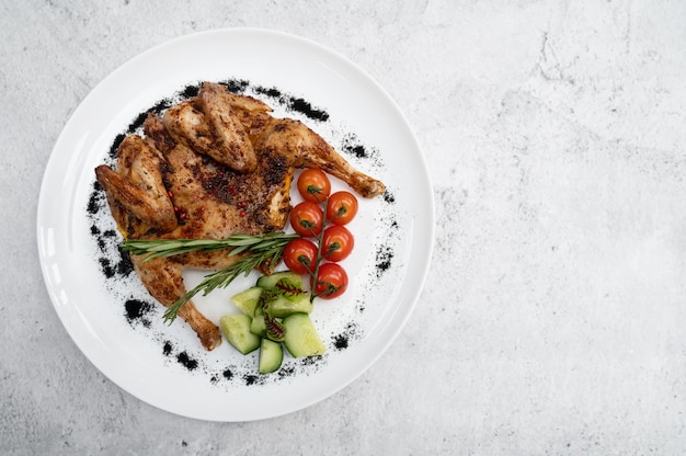 Grilled fried chicken tabaka and fresh vegetables on white plate