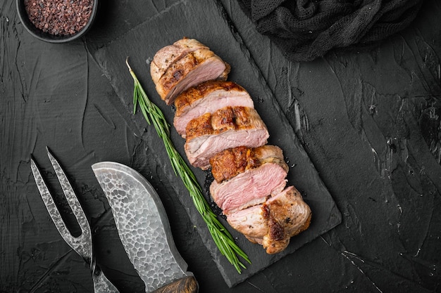 Grilled goose breast on stone serving board on black stone background top view flat lay with copyspace and space for text