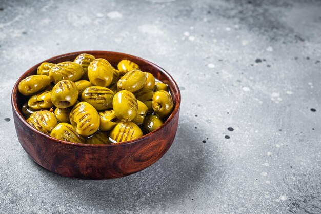 Grilled green organic olives. Gray background. Top view. Copy space.