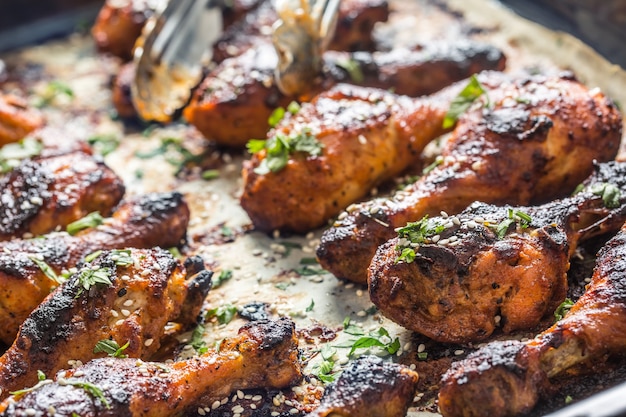 Grilled hicken legs BBQ with spices herbs and sesame on baked paper. Roasted poultry meal in roaster dish.