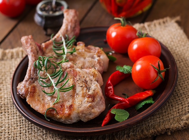 Grilled juicy steak on the bone with vegetables on a wooden background.