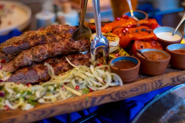 Grilled kebab on skewers with spices and grilled vegetables sauces and fresh onions with pomegranate A huge portion for a large company at the restaurant