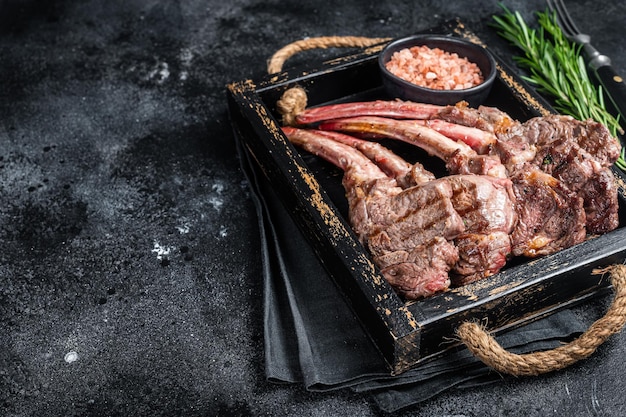 Grilled lamb chop steak mutton meat cutlet in wooden tray Black background Top view Copy space