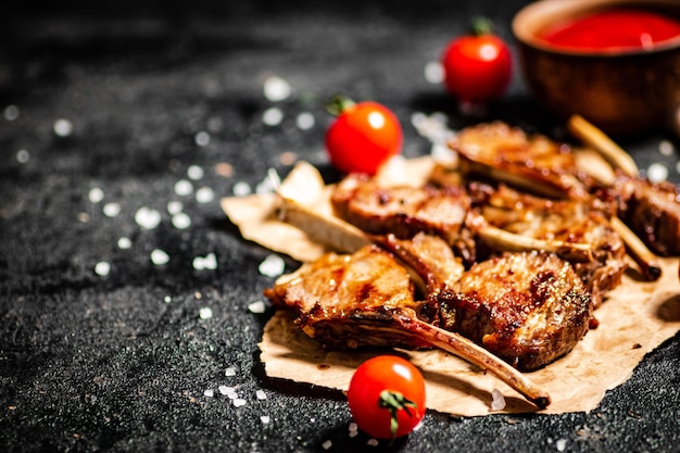 Grilled lamb rack on paper with tomato sauce and cherry tomatoes