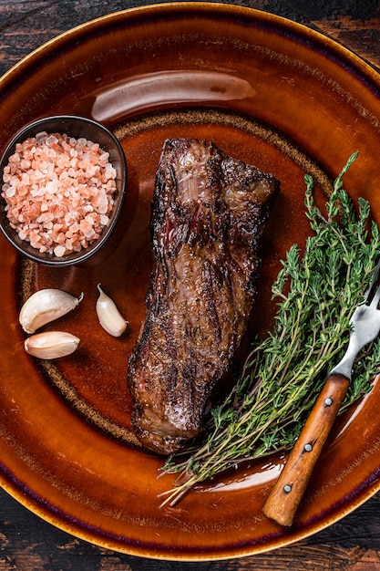 Grilled machete skirt beef steak on rustic plate with herbs and pink salt