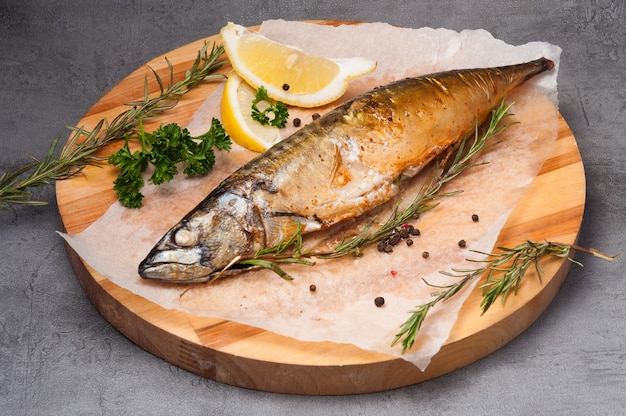 Grilled mackerel with lemon and rosemary on a wooden board