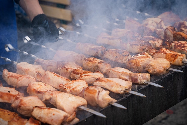 Grilled marinated pork skewered meat being prepared on outdoor barbeque grill with smoke