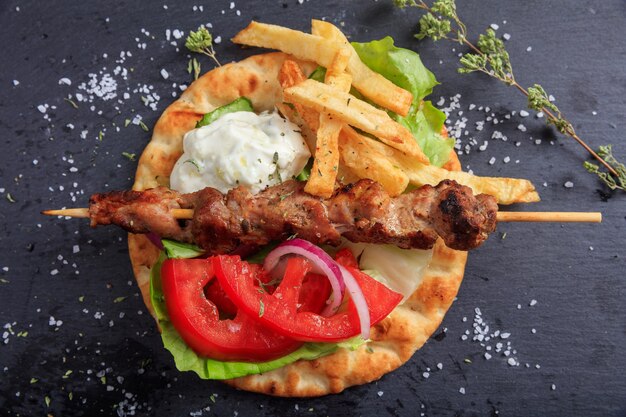 Grilled meat skewer on a pita bread top view