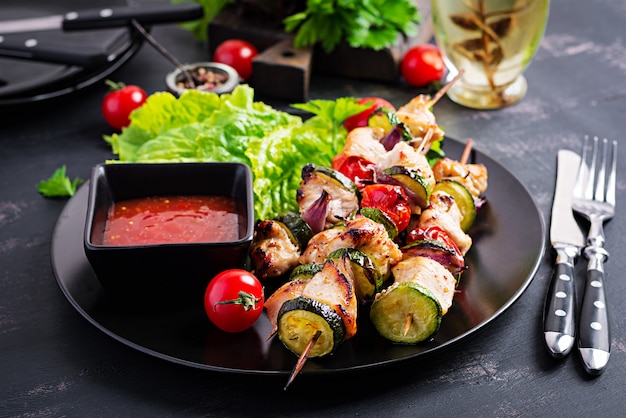 Grilled meat skewers, chicken  shish kebab with zucchini, tomatoes and red onions.