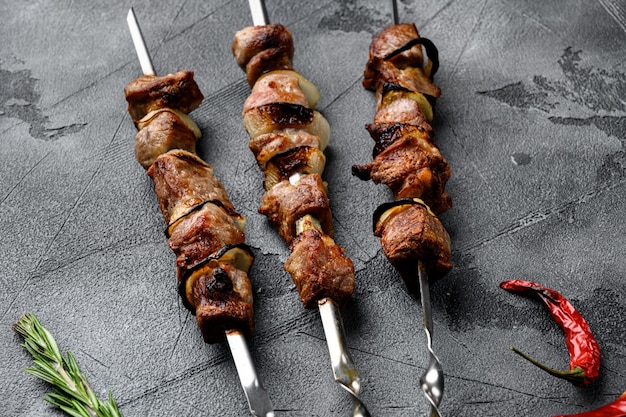 Photo grilled meat skewers, shish kebab with onion set, on gray stone table background