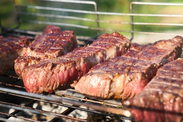 Grilled meat on a wire rack. Steaks barbecue on a brazier with natural smoke. Outdoor cooking.