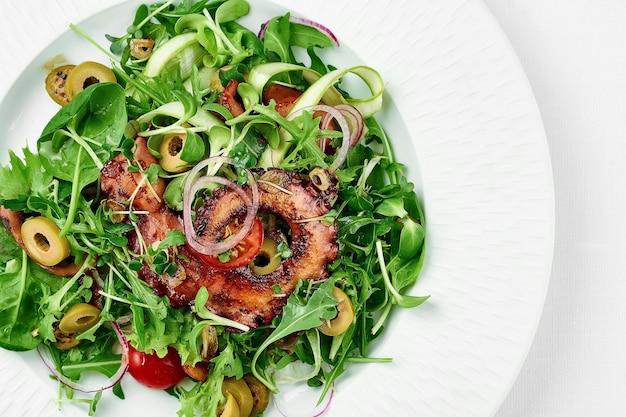 Grilled octopus salad on a white plate on a white tablecloth Closeup selective focus