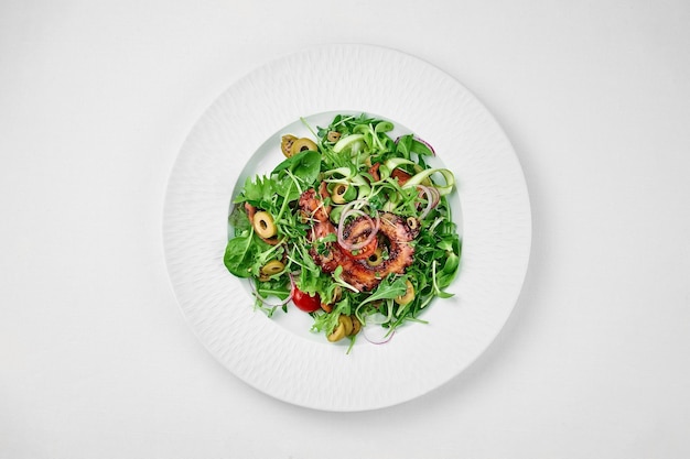 Grilled octopus salad on a white plate on a white tablecloth Closeup selective focus