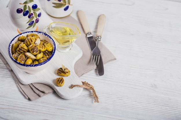 Grilled olives with garlic olive oil and spices on white rustic table