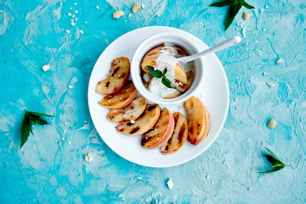 Grilled peach with ice creame on white plate