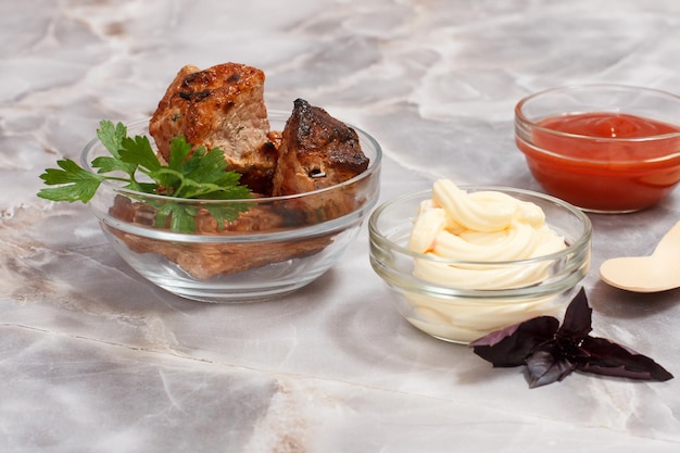 Grilled pork in a bowl with sauces and greens