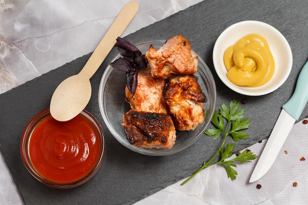 Grilled pork in a bowl with sauces and greens