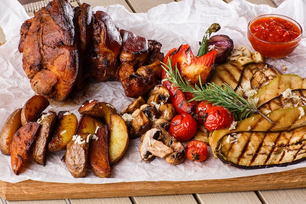 Grilled pork knuckle with grilled tomatoes, champignons, vagetable marrow, eggplant, red sweet pepper and baked potatoes