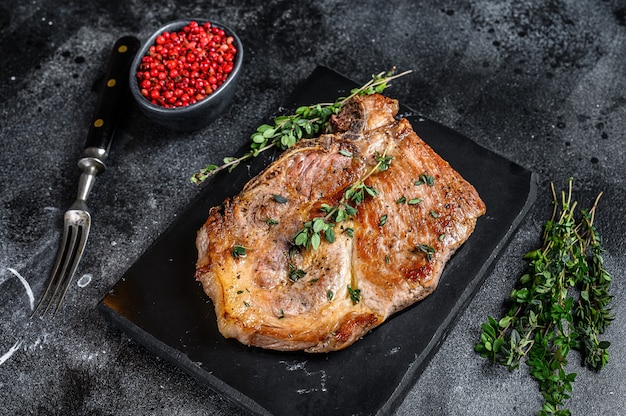 Grilled pork loin steak on a marble board. Black background. Top view.